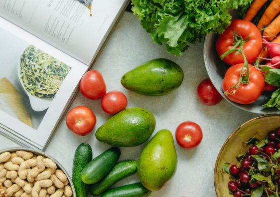 An appetizing display of fresh fruits and vegetables with a cookbook, perfect for healthy recipes.
