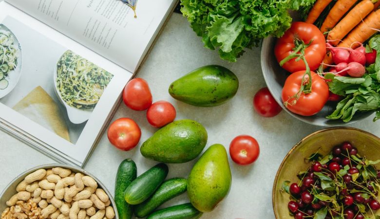 An appetizing display of fresh fruits and vegetables with a cookbook, perfect for healthy recipes.
